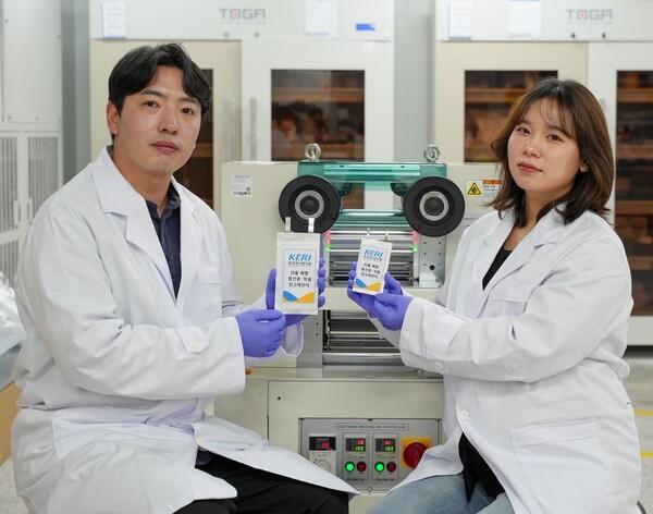 사진왼쪽부터 KERI 남기훈 박사와 김가람 연구원(UST 석사과정 졸업)이 중간층을 만드는 롤프레스 장비 앞에서 성과물을 선보이고 있다. [사진=전기연구원]" height="472" loading="lazy